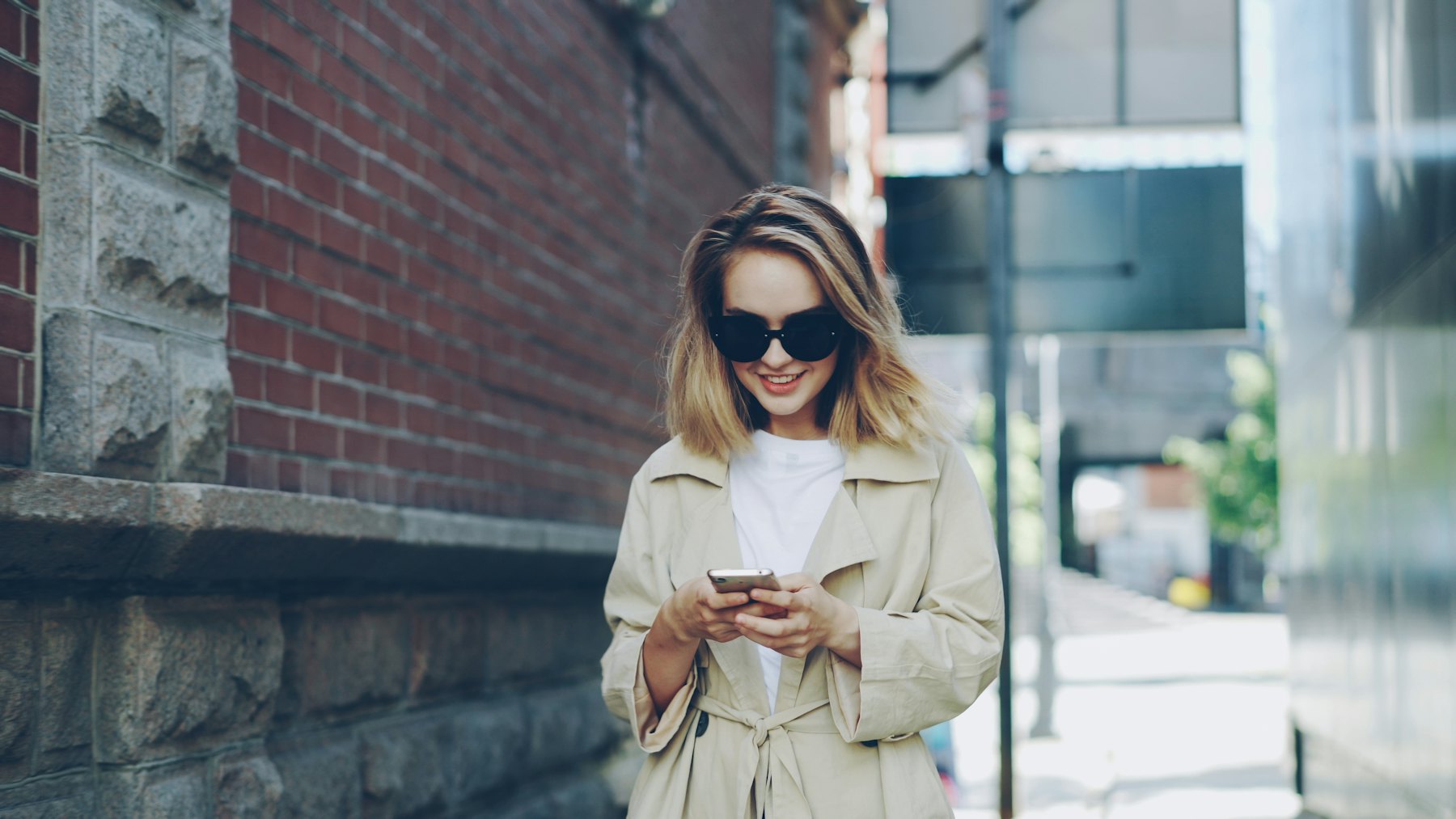 Smiling woman walking through the city, looking at her phone
